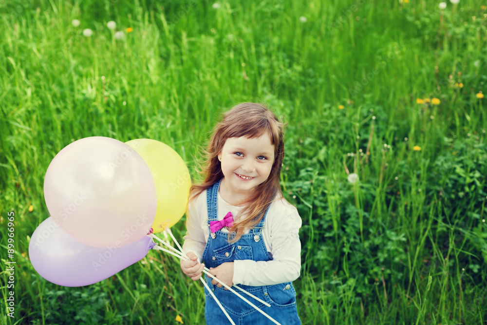 portrait of cute little girl with beautiful smile holding toy balloons in hand on the flower meadow, happy childhood concept, child having fun, vintage toned portrait of cute little girl with beautiful smile holding toy balloons in hand on the flower meadow, happy childhood concept, child having fun, vintage toned