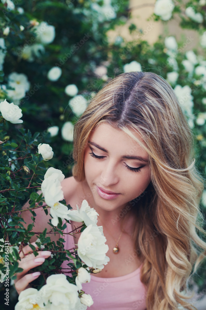 beautiful woman with long curly hair smells white roses outdoors, closeup portrait of sensual girl face, blonde female portrait with flowers, elegant lady in blossom garden beautiful woman with long curly hair smells white roses outdoors, closeup portrait of sensual girl face, blonde female portrait with flowers, elegant lady in blossom garden