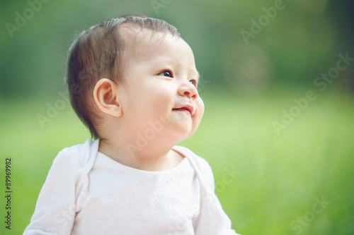 Cute asian baby laughing in garden  soft focus on the eyes 