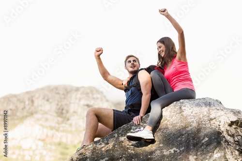 Young happy joggers sitting on rock cheering 