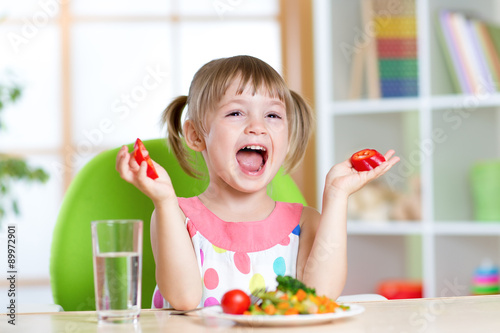 kid eating healthy vegetables food at home or kindergarten