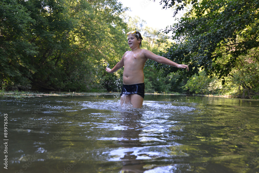 Boy teenager swims in river in summer Boy teenager swims in river in summer