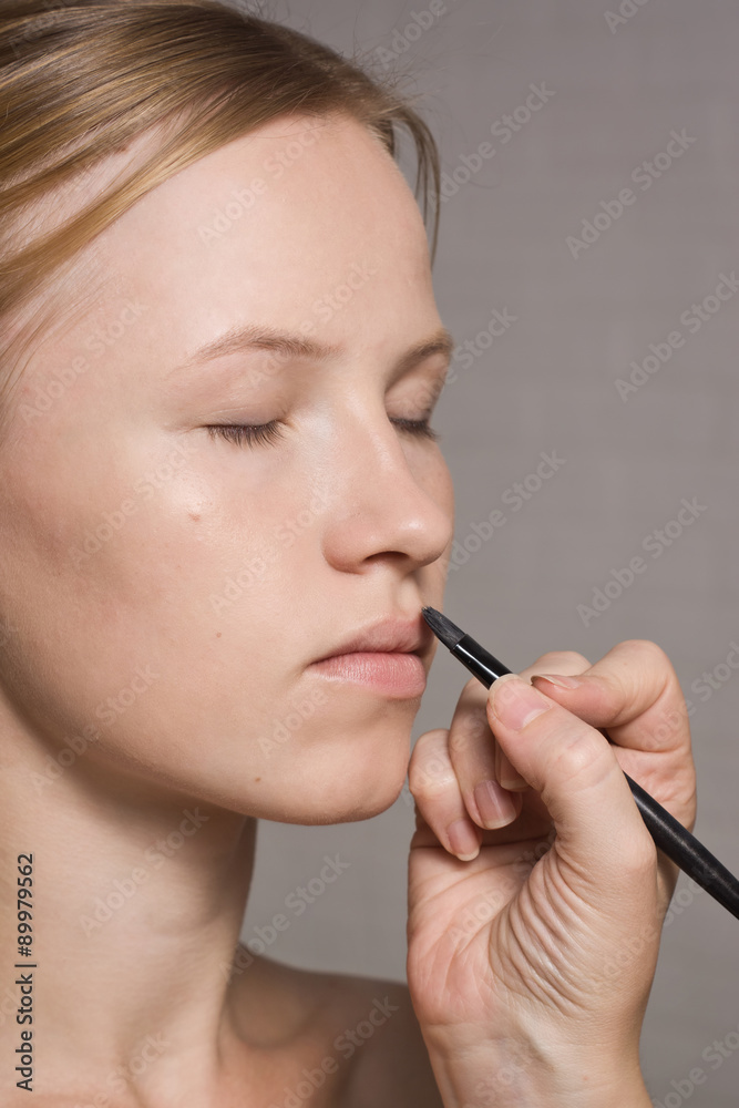 Beautiful woman having lipstick applied by make-up artist Beautiful woman having lipstick applied by make-up artist