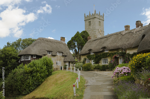 Canvas Print The pretty thatched cottages of Church Hill, with All Saints church in the background