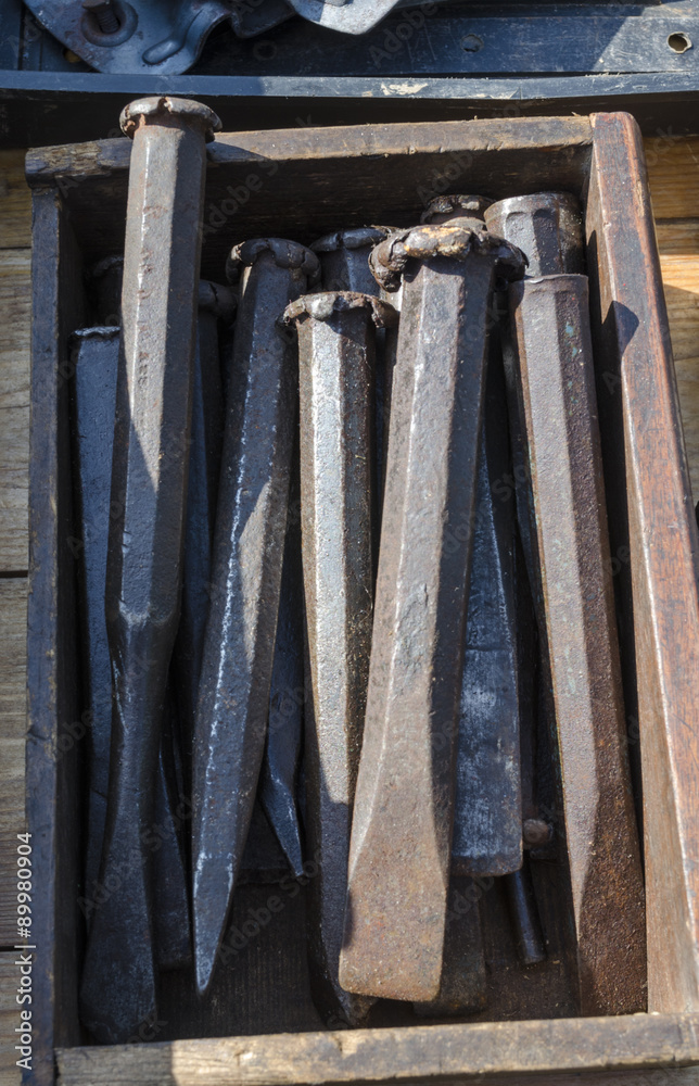 A selection of old cold chisels in a wooden box at a car boot sale