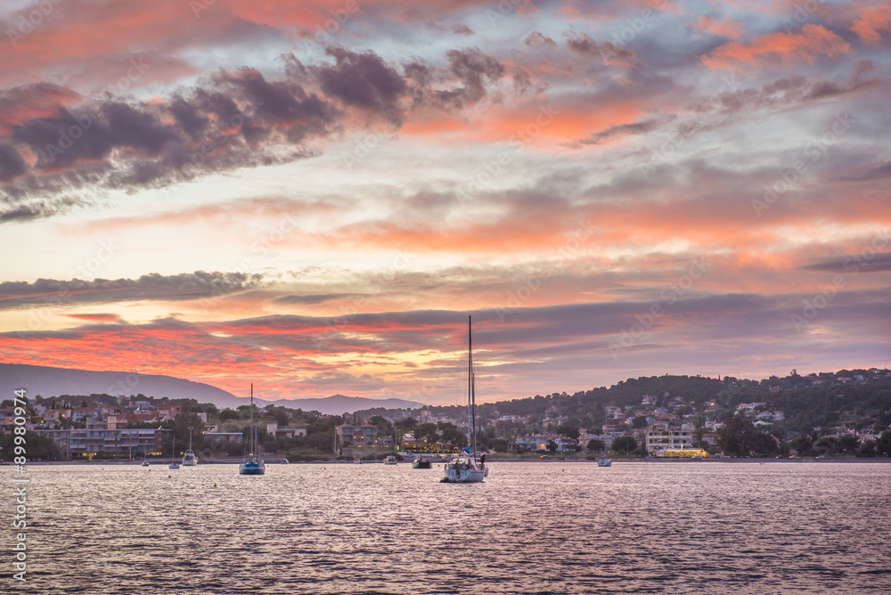 Boats in bay of porto rafti under a fired cloudscape at sunset