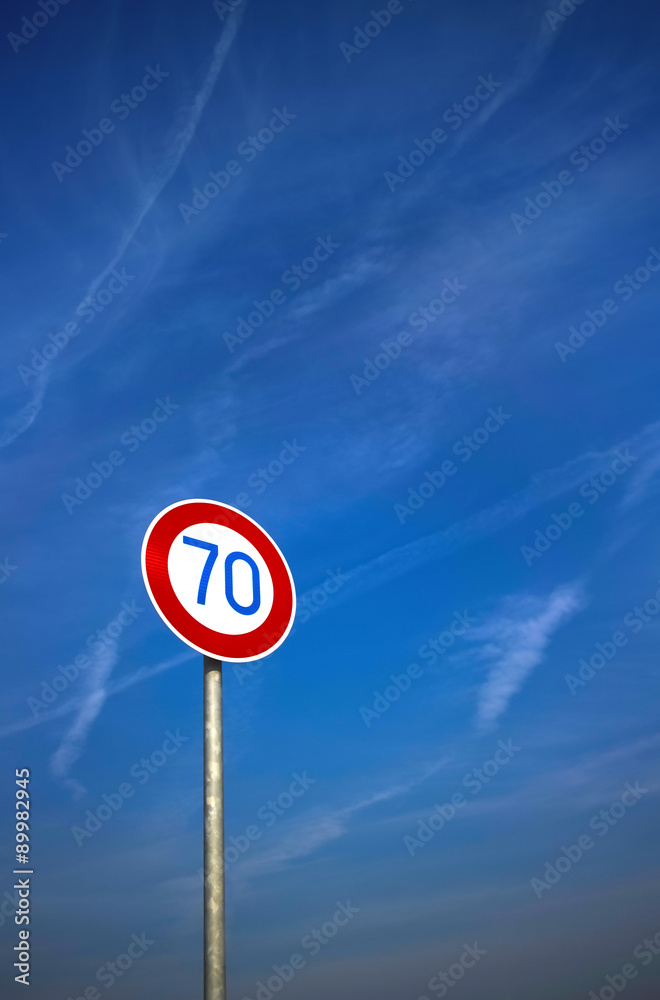 Road sign against blue sky with contrails