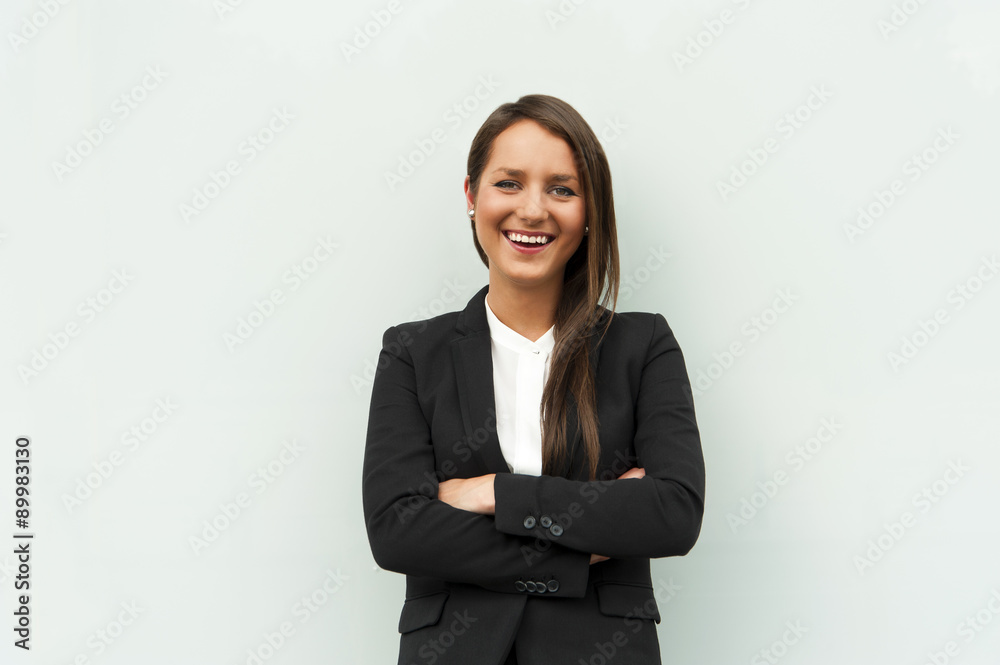 Business woman by the glass wall in the city smiling at camera. Business woman by the glass wall in the city smiling at camera.