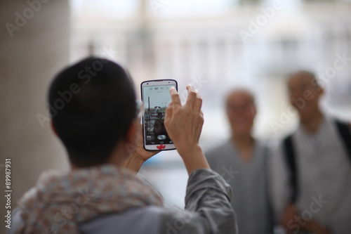 Young man taking picture of his friends with smartphone