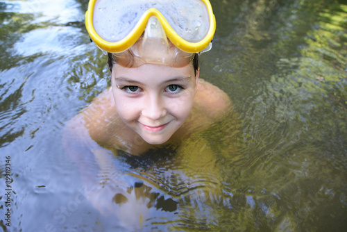 Boy teenager swims in river in summer