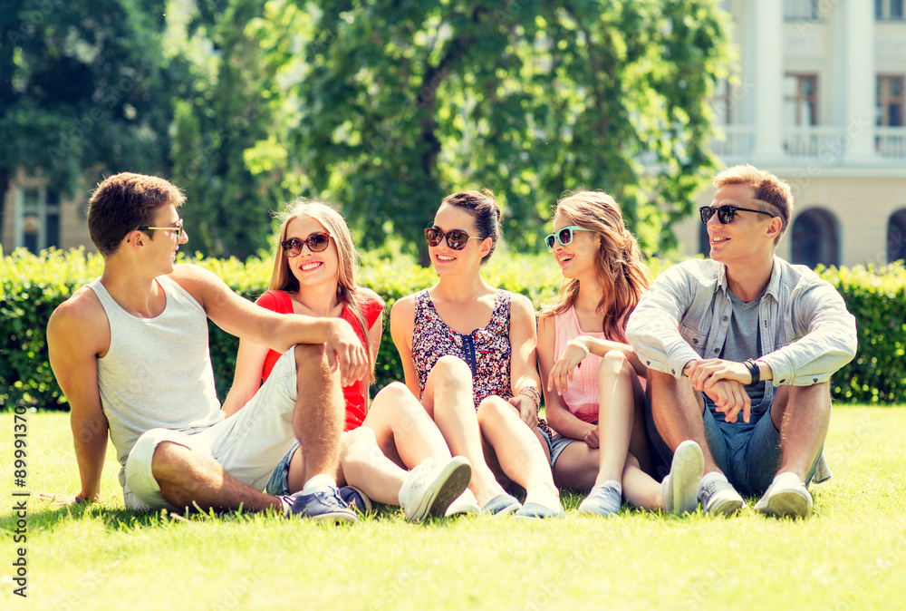 group of smiling friends outdoors sitting on grass group of smiling friends outdoors sitting on grass