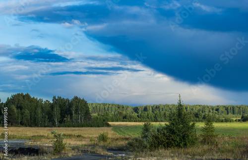 layers of storm clouds on the background fields and forests