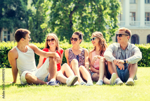 group of smiling friends outdoors sitting on grass