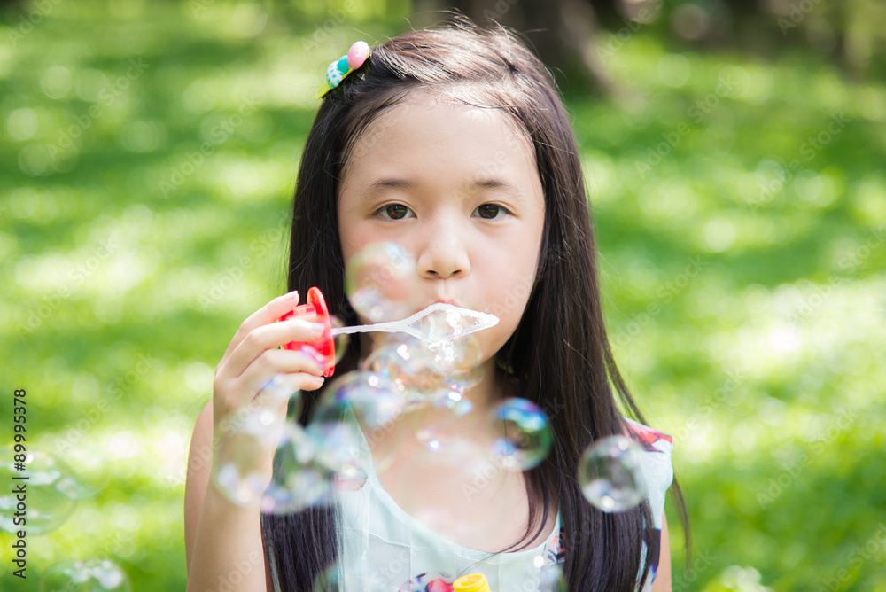 Cute asian girl is blowing a soap bubbles