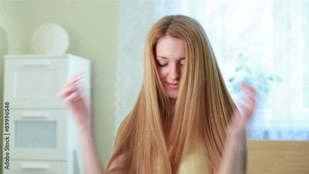 Charming young red-haired woman combing her long hair and smiling Charming young red-haired woman combing her long hair and smiling