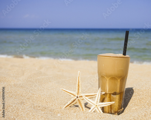 Iced coffee on a sandy beach background photo