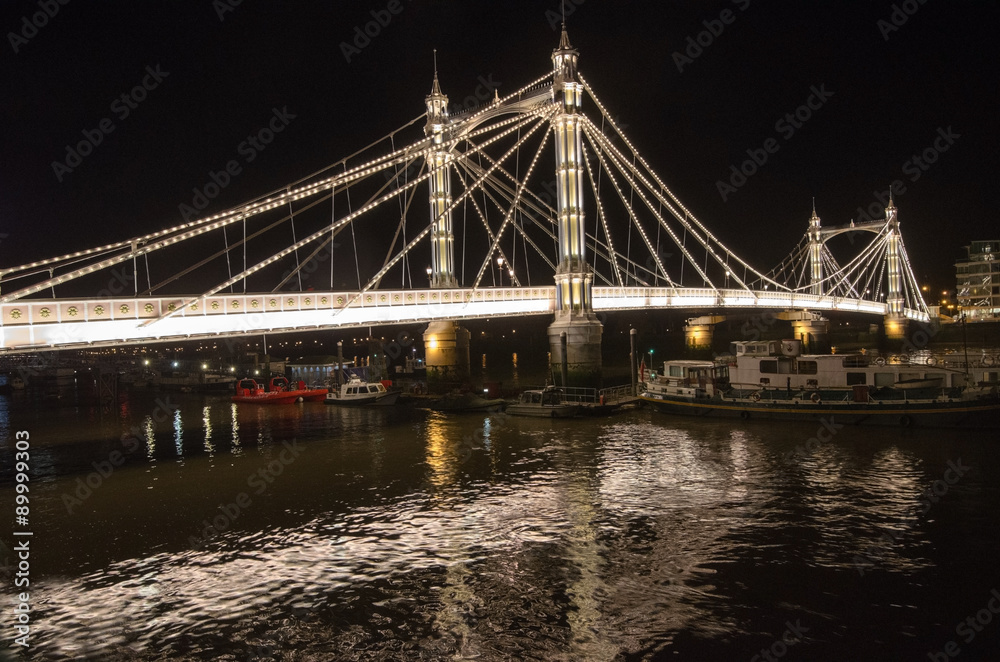 Albert Bridge, illuminated at night spans the River Thames, London.