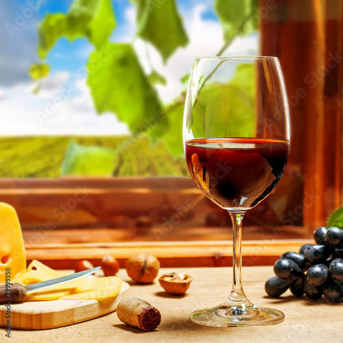 Wine in glass with cheese, grape and nuts on table
