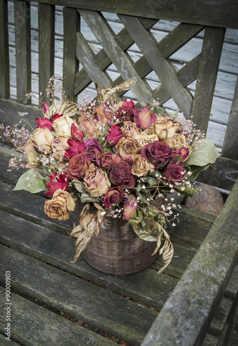 Bouquet of dry vintage roses on old bench