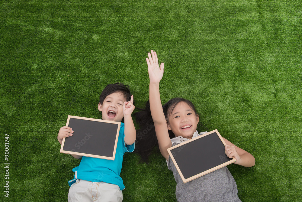 Cute asian children lying and holding blackboard Cute asian children lying and holding blackboard