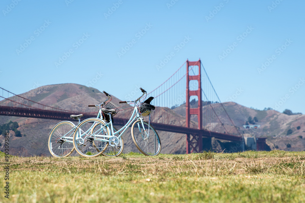 Two bicycles parked on grass in front of Golden Gate Bridge Two bicycles parked on grass in front of Golden Gate Bridge