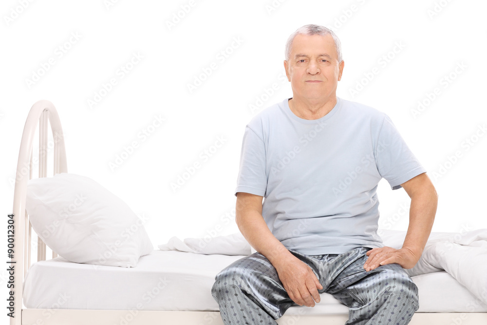 Senior man in pajamas sitting on a bed