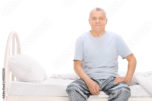 Senior man in pajamas sitting on a bed © Ljupco Smokovski