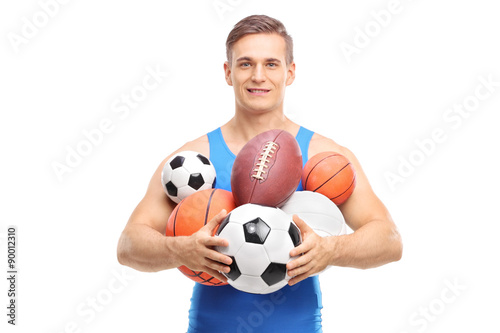 Young athlete holding a bunch of different kinds of sports balls