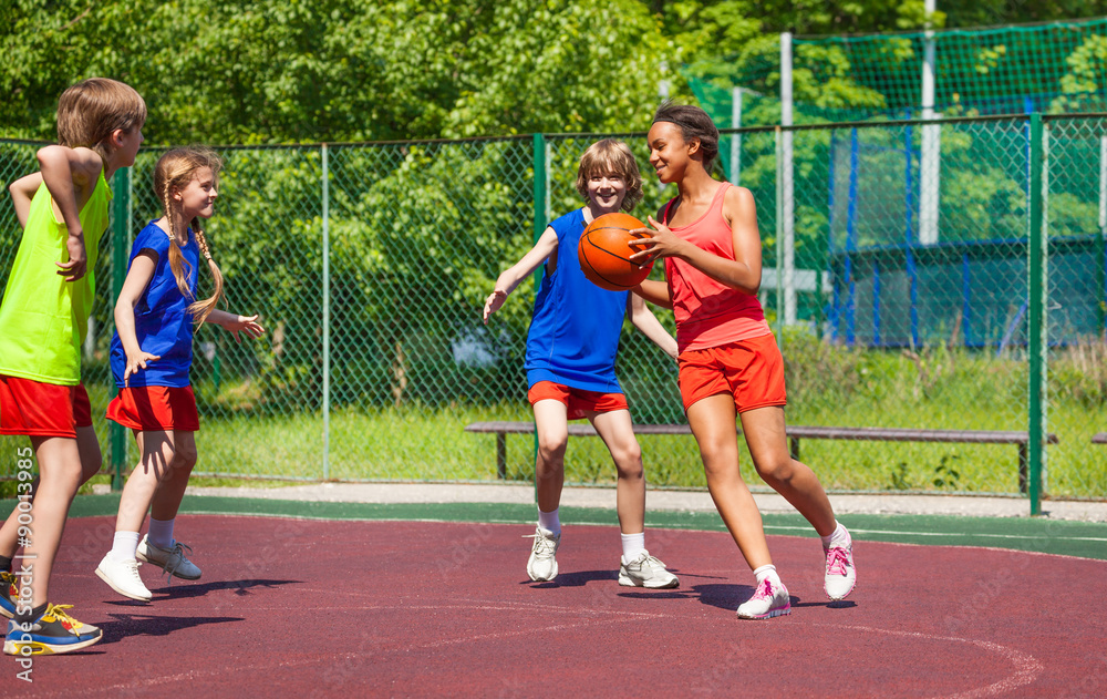 African girl holds ball and teens play basketball
