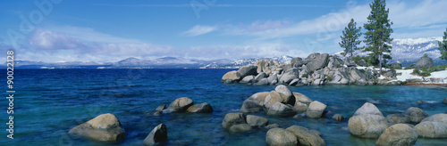This is Lake Tahoe after a winter snow storm. There is a full moon over the lake and snow on the sandy shore. #90022128