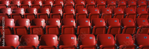 These are bright red outdoor stadium seats with seats that fold up. They are located at a baseball stadium.
