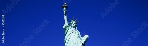 This is the top half of the Statue of Liberty against a blue sky in horizontal format.