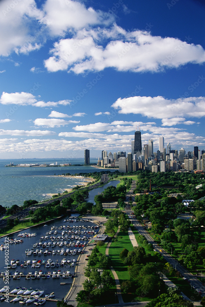 Naklejka premium This shows Lincoln Park, Diversey Harbor, and Lake Michigan looking south toward the skyline. It has morning light in summertime. There are boats moored in the harbor next to the lake.