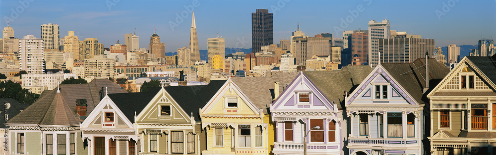 These are the historic Victorian homes in front of the skyline on Steiner Street. They are painted pastel colors and line up next to each other in row house formation. These are the historic Victorian homes in front of the skyline on Steiner Street. They are painted pastel colors and line up next to each other in row house formation.
