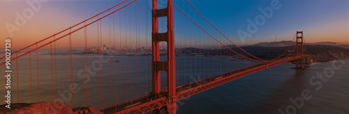 This is the Golden Gate Bridge at sunset. It is the view from the Marin Headlands. The skyline is small in the distance.