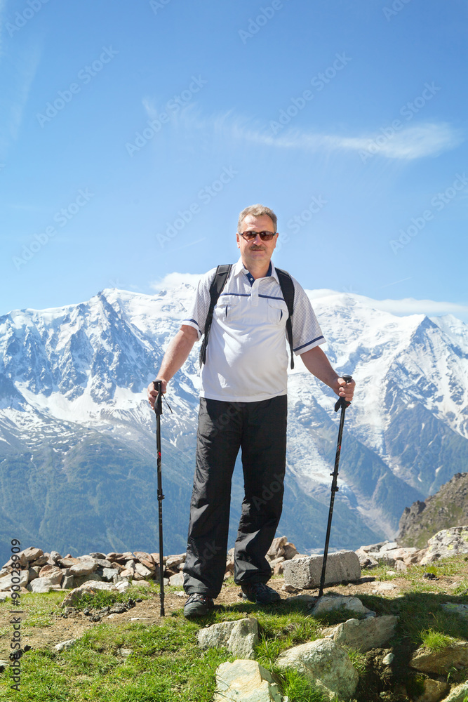Mature tourist staying on a cliff in Alps
