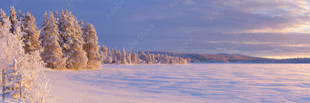 Naklejka premium Frozen Äijäjärvi lake in Finnish Lapland in winter at sunset