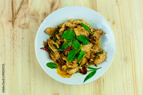 Spicy Thai basil chicken ready to eat on traditional plate with wooden spoon. Top View. (Shallow aperture intended for the aesthetic quality of the blur.)