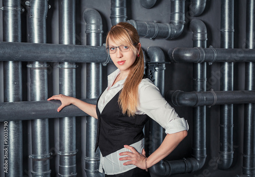 Attractive young businesswoman wearing glasses standing near PVC pipes construction