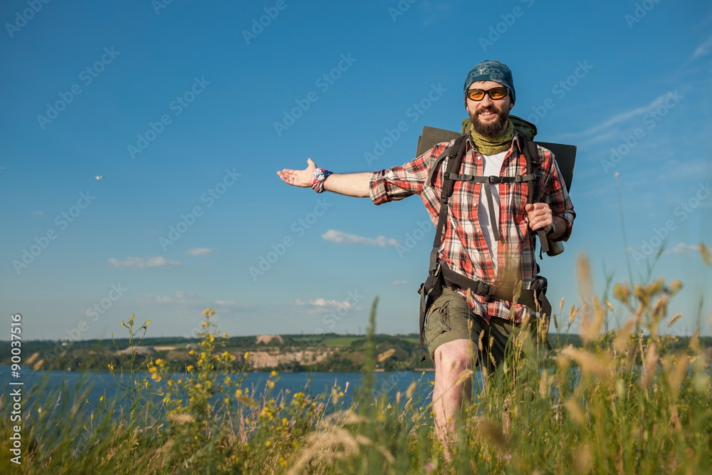 Naklejka premium Young caucasian man with backpack standing on the top of hill