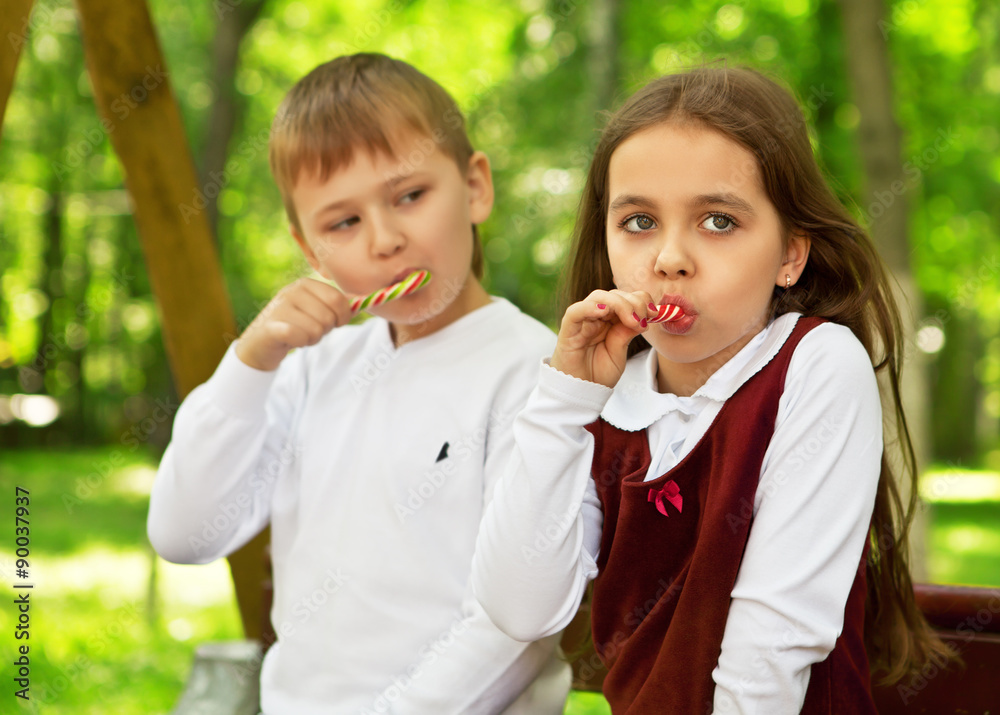 A girl with a boy sitting on a Park bench, eating caramel sticks A girl with a boy sitting on a Park bench, eating caramel sticks