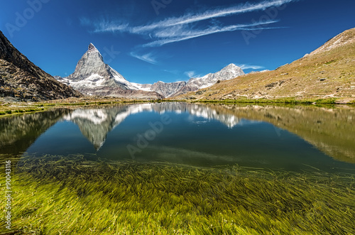 Matterhorn mountain behind a beautiful lake with grass