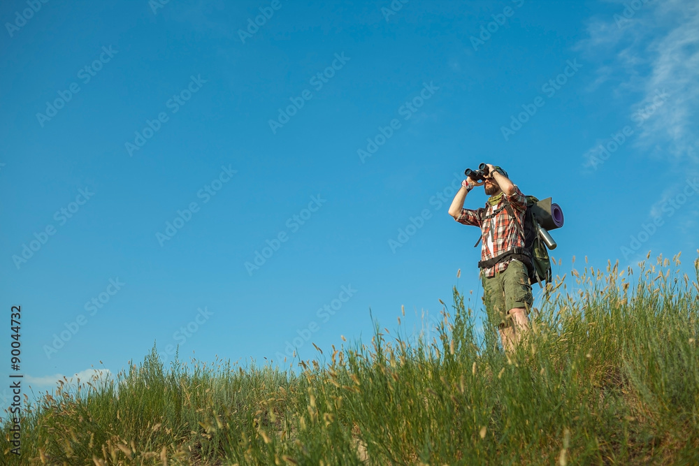 Young caucasian man with backpack standing on the top of hill Young caucasian man with backpack standing on the top of hill