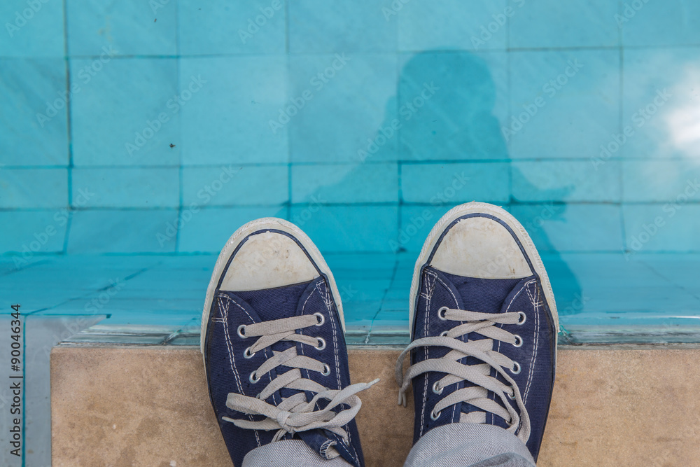 View of male feet at swimming pool side.
