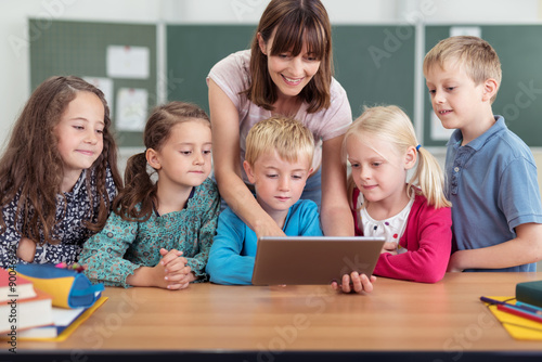 lehrerin zeigt kleinen kinder etwas am tablet photo