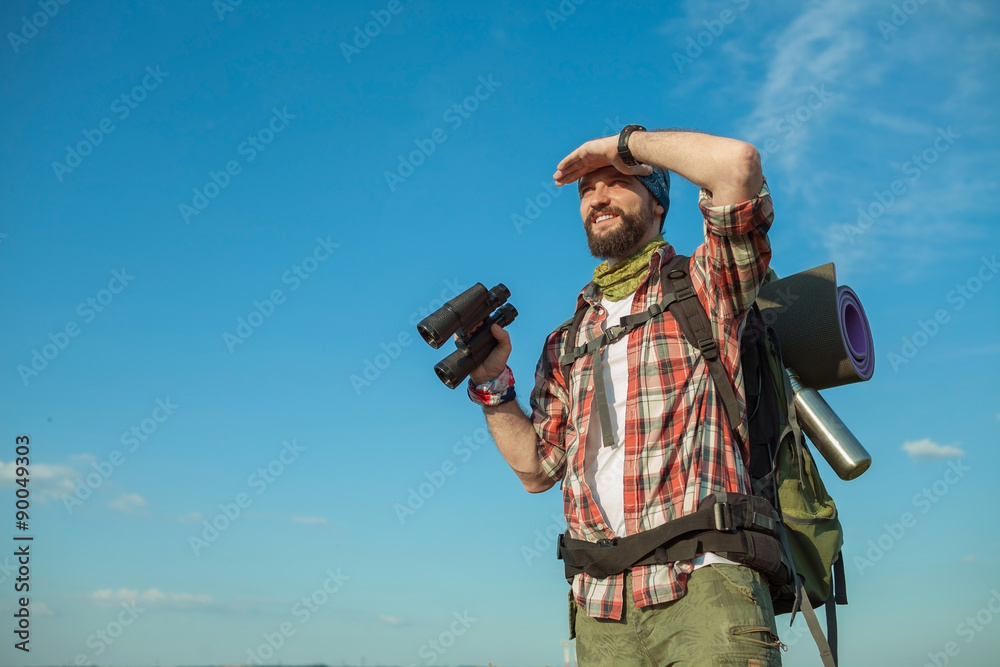 Obraz premium Young caucasian man with backpack standing on the top of hill