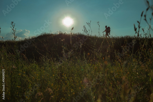 Young caucasian man with backpack walking on a green meadow