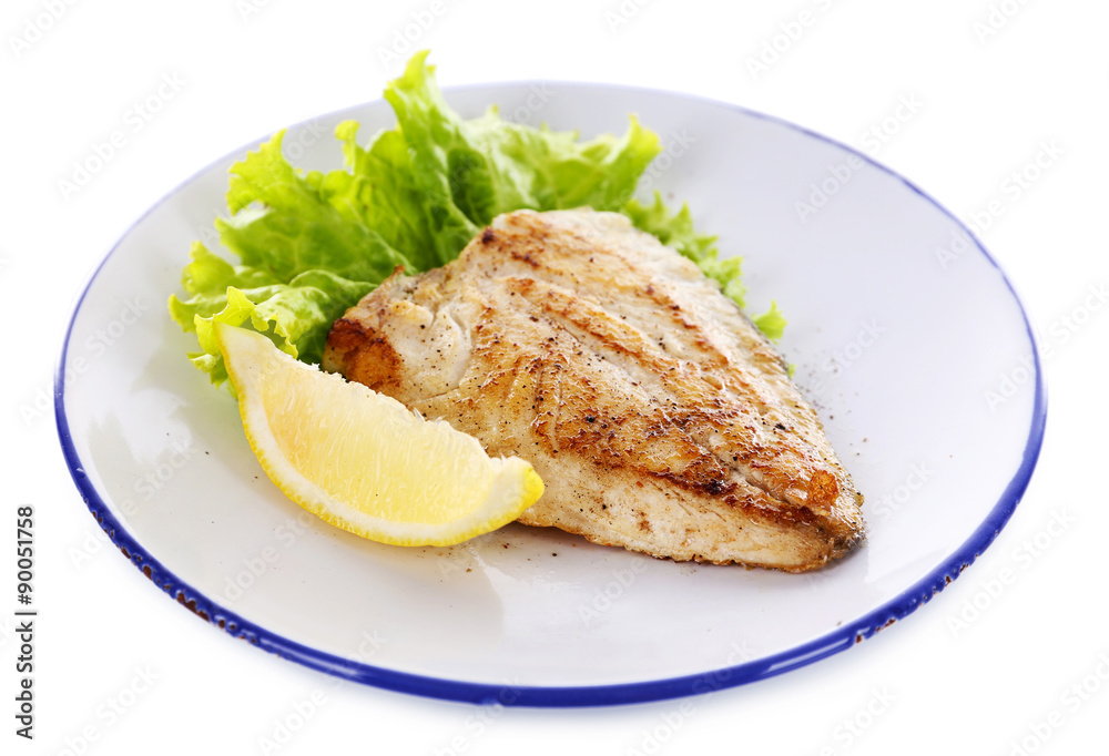 Dish of fish fillet with lettuce and lemon on plate close up