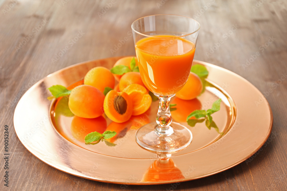 Glass of apricot juice and fresh fruits on table close up