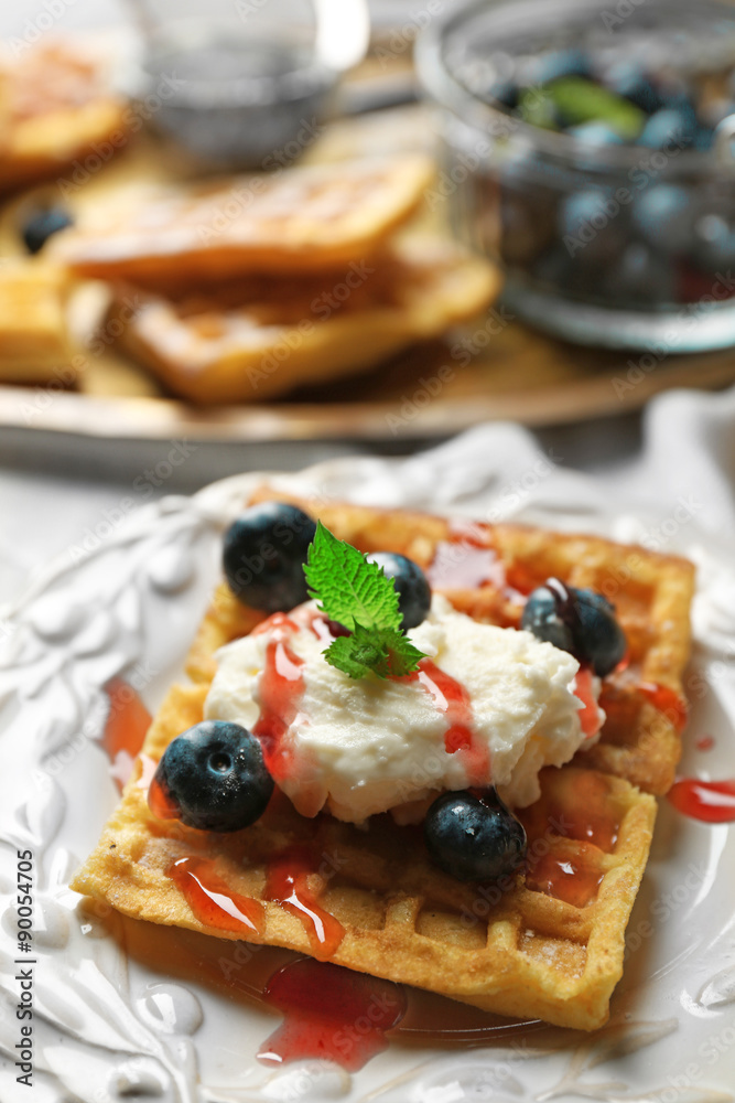 Sweet homemade waffles on plate, on color wooden background Sweet homemade waffles on plate, on color wooden background